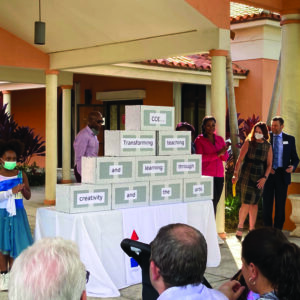 A group of people standing around a table with boxes in front of them.