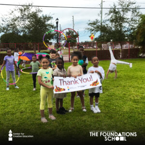 A group of thankful children posing with hula hoops and a thank you sign.