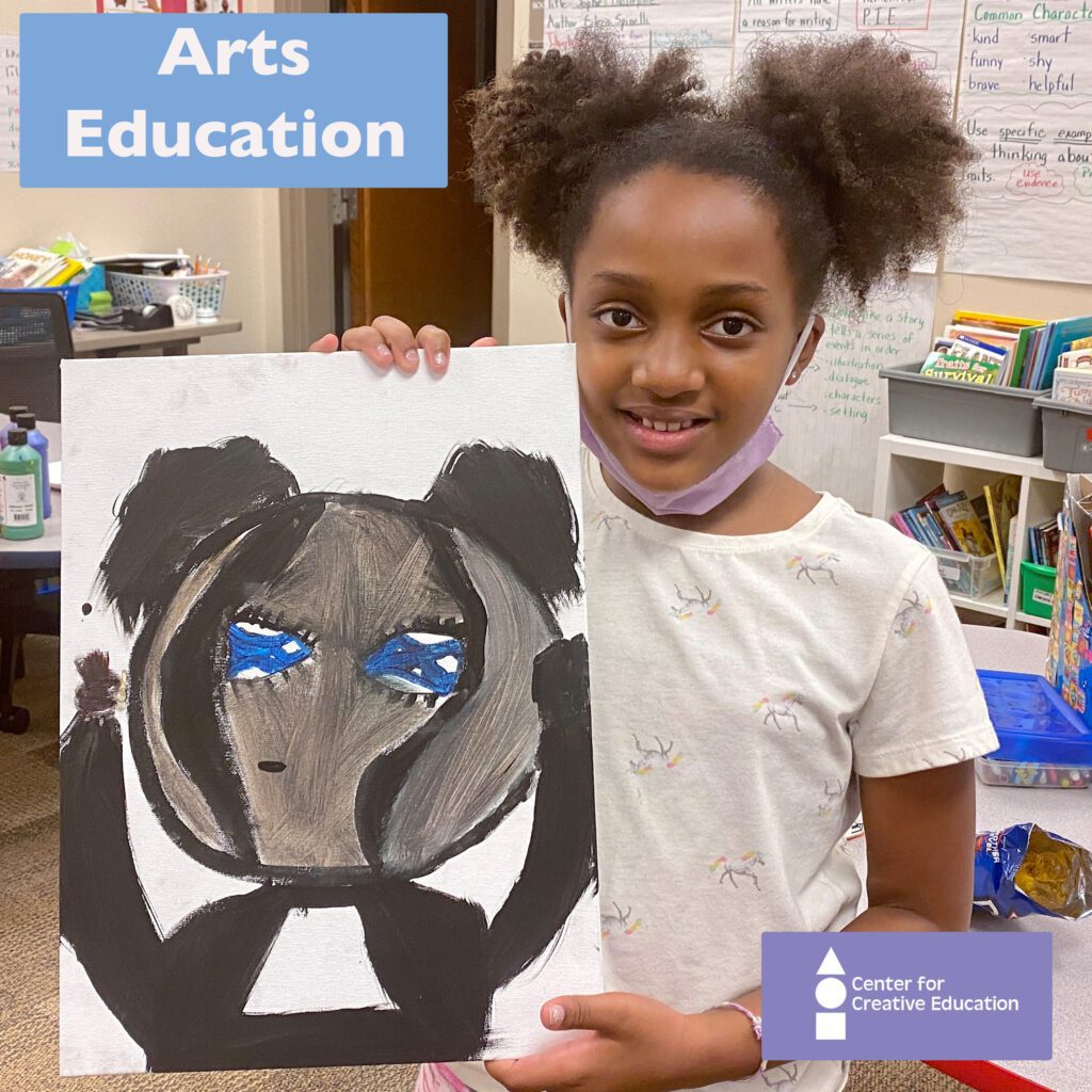 A young girl enthusiastically presents her carefully crafted artwork of a panda bear, showcasing the transformative power of arts education.