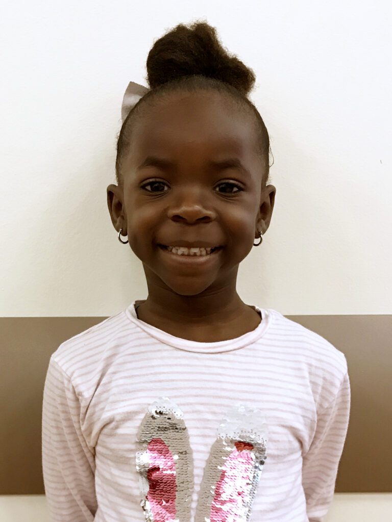 A young girl showcasing her creativity in education while wearing a pink bunny shirt.