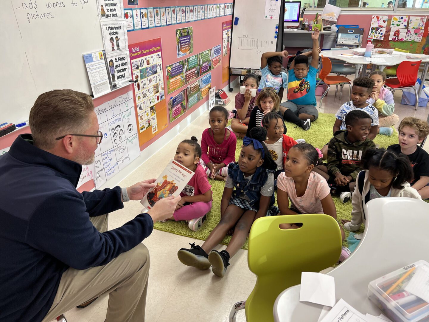 A man reading a book to children in a classroom during a year-end appeal event.