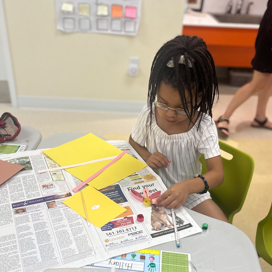 A young girl at The Foundations School table making crafts.