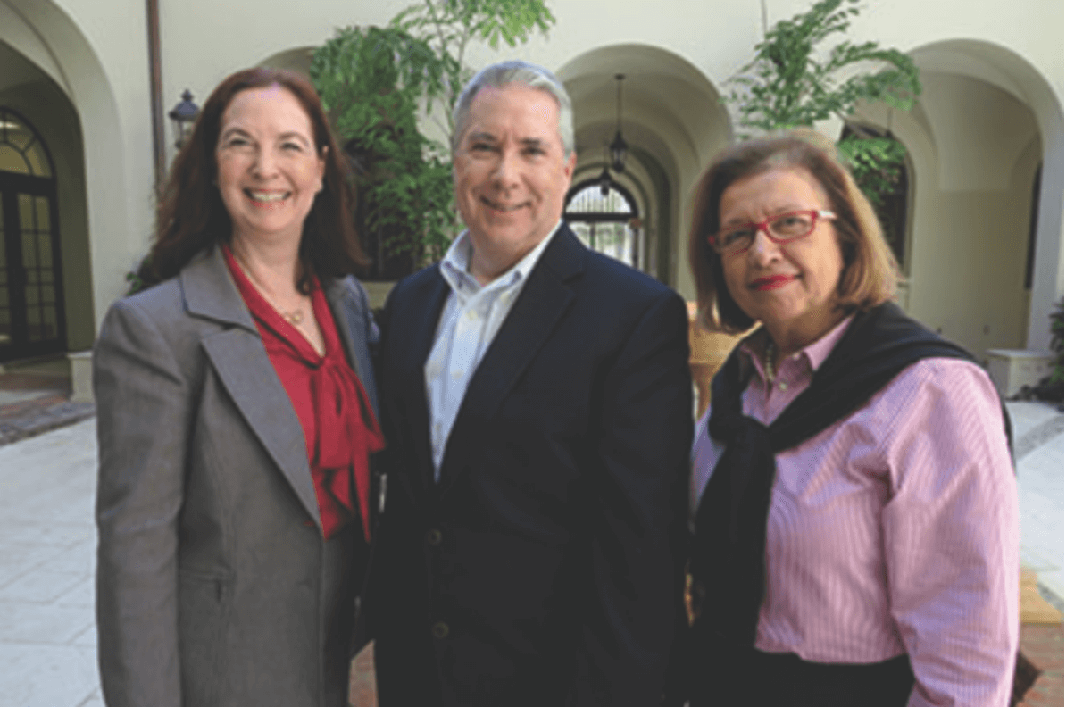 Three business people standing in front of a building, delivering a message from the president.