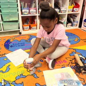 A girl is sitting on the floor in a classroom.