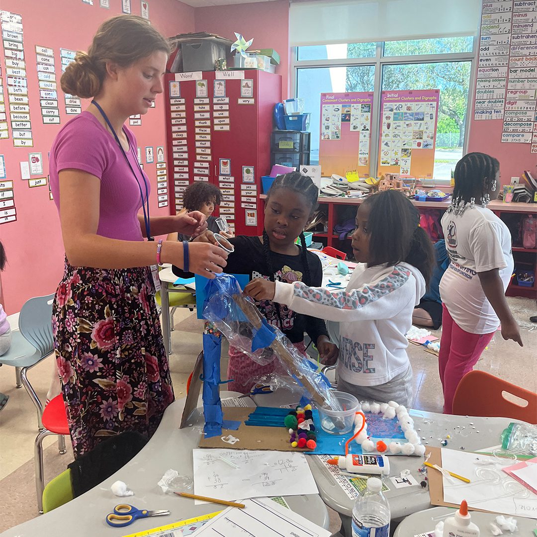 A group of children are working on a project in a classroom that resembles a playground.