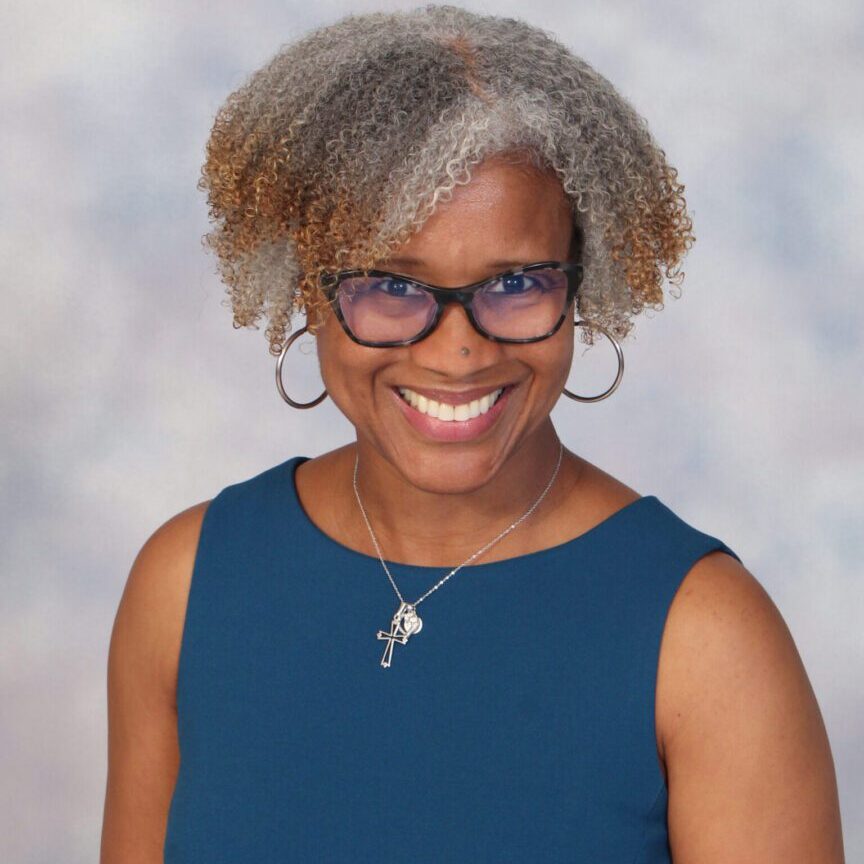 Smiling woman with gray hair and glasses.