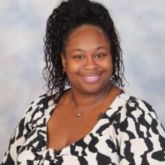 Smiling woman in black and white blouse.