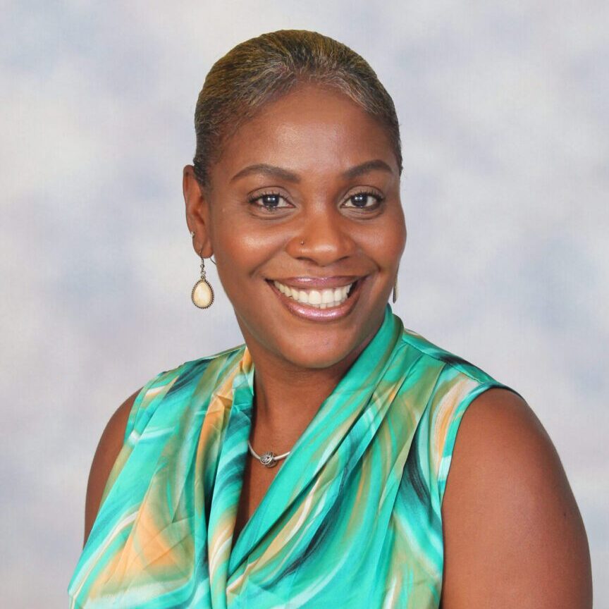 Smiling woman in a green patterned top.