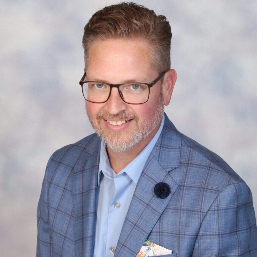 Smiling man in a blue plaid suit.