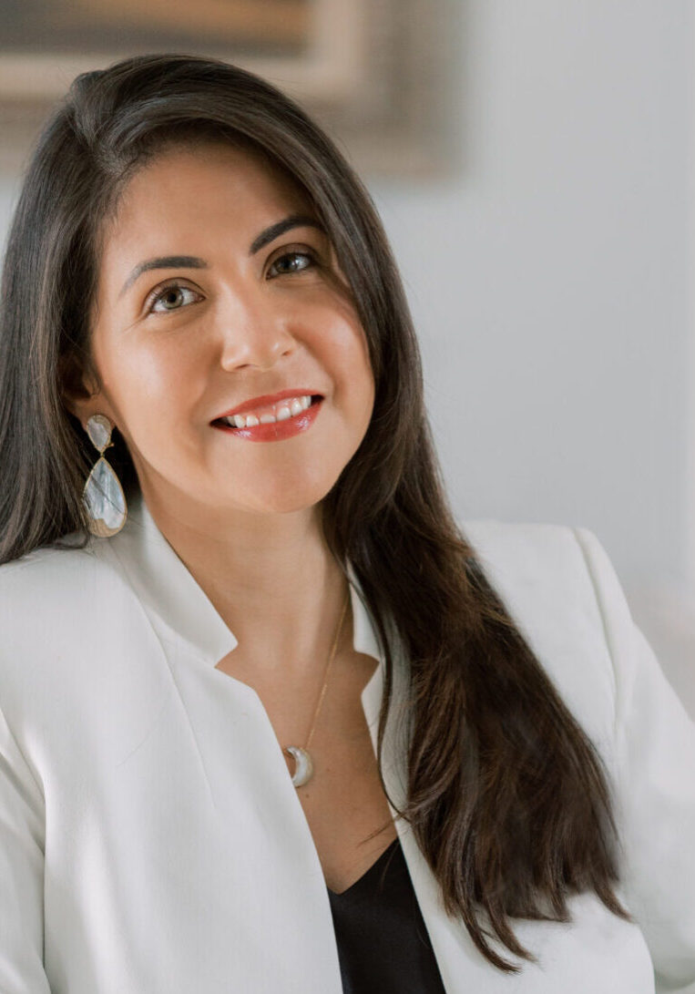 Smiling woman wearing a white blazer.