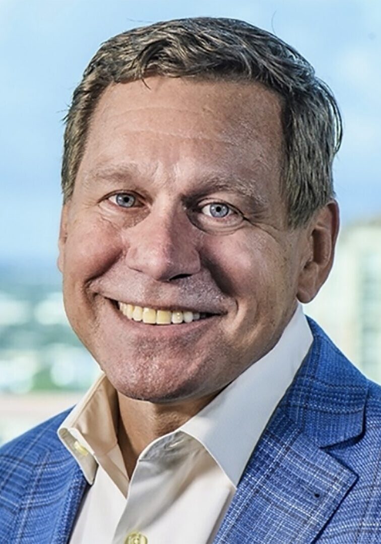 A man in a blue suit smiling in front of a city, possibly as a member of the board of directors.