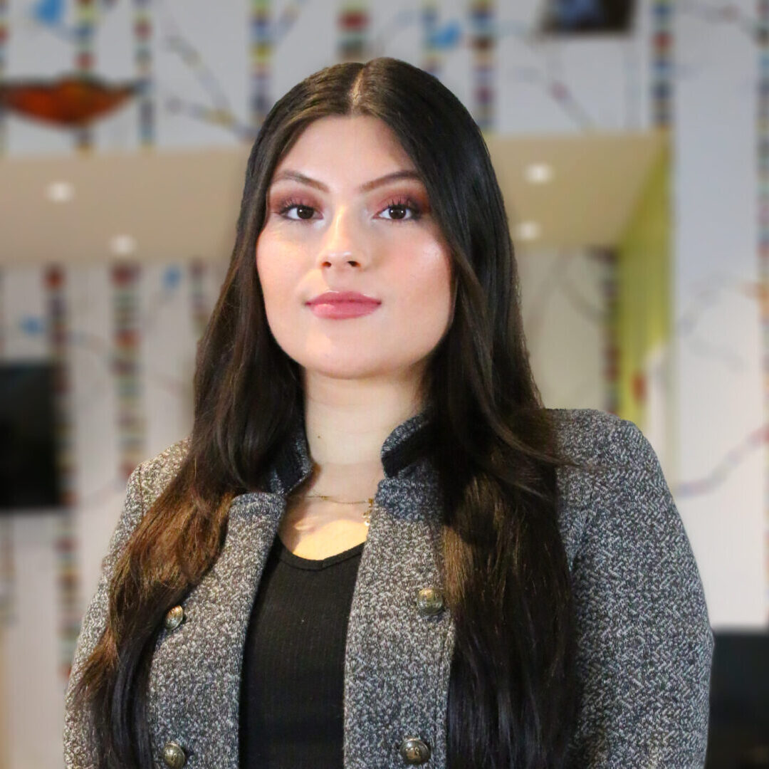 A teaching artist in a grey jacket standing in an office.