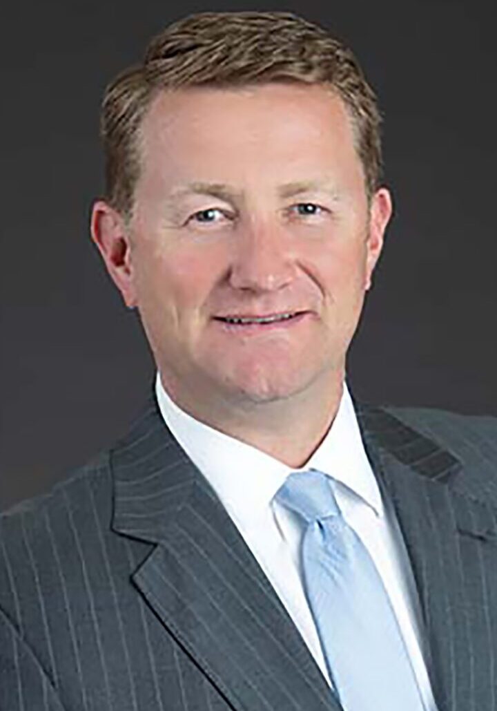 A man in a suit and tie is posing for a photo with the board of directors.