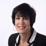 Smiling woman in black blazer and white collar.