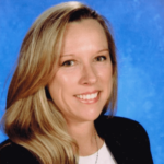 Woman with blonde hair smiling in a suit.