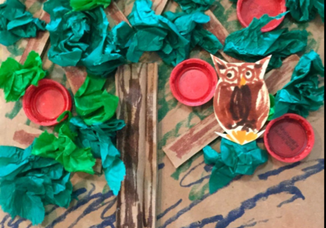 A virtual owl perched on a tree with vibrant red and green leaves.