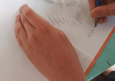 A hand digitally creating virtual art on a piece of paper.