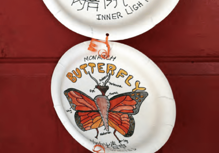 Three paper plates with virtual insects on them hanging on a door.